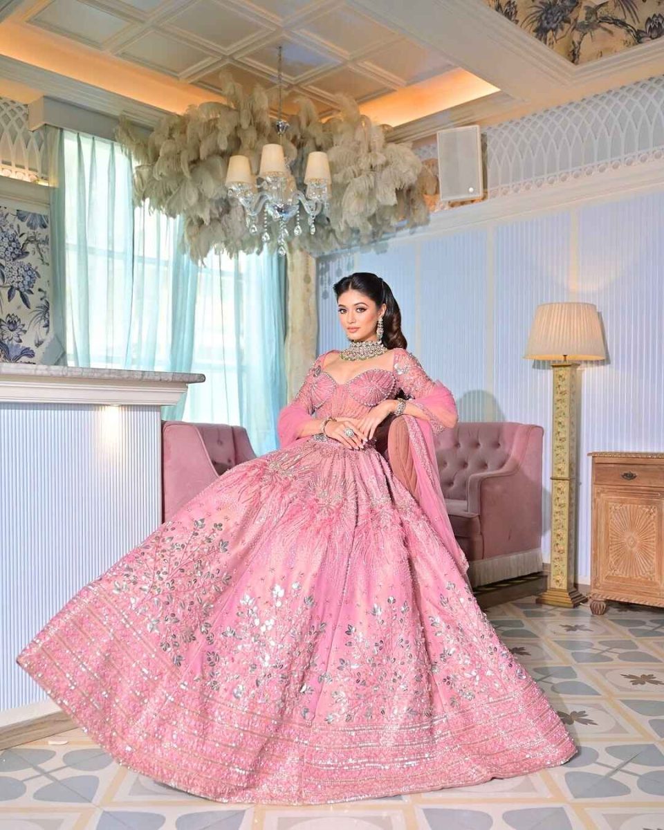 Bride in a pink embellished lehenga seated in a luxury suite, bridal photoshoot in Mumbai